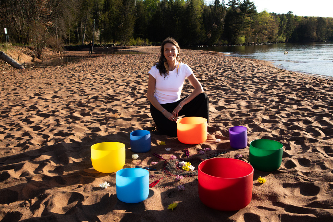 woman sitting on beach with sounding bowls